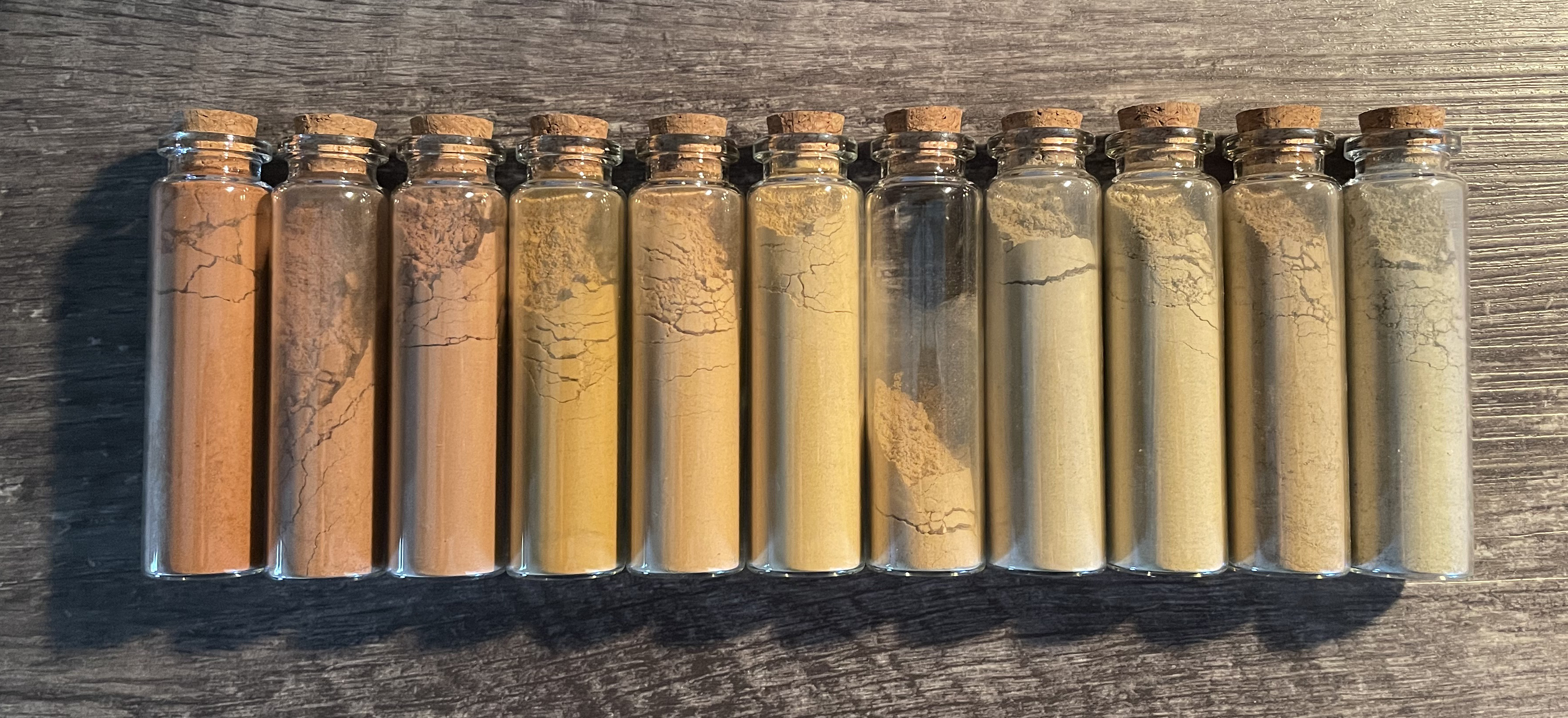 Different coloured pigments in glass jars with cork stoppers.